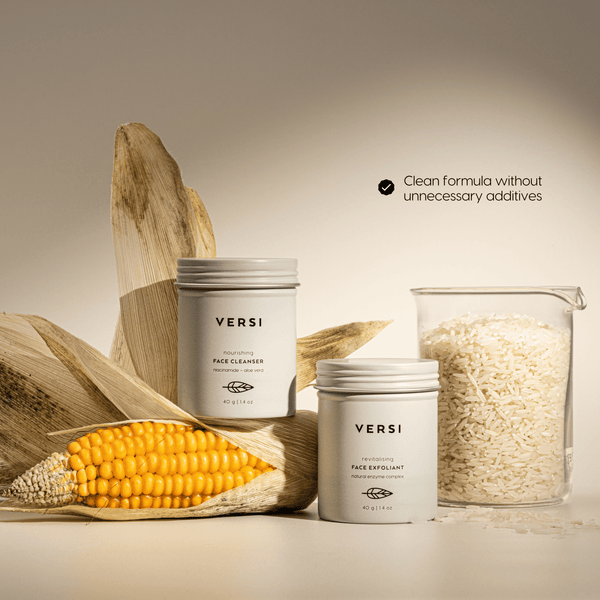 Two Versi skincare jars arranged with a corn cob, and a glass container of rice grains on a warm beige background. Text on the right reads 'Clean formula without unnecessary additives'.