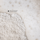 Close-up of exfoliating powder resting on a white foamy surface with small bubbles and the text 'Ultra-concentrated powder exfoliant' near the top left.